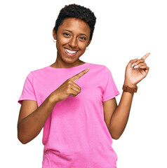 Wall Mural - Young african american woman wearing casual clothes smiling and looking at the camera pointing with two hands and fingers to the side.