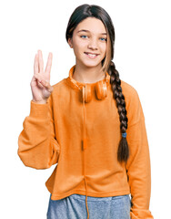 Canvas Print - Young brunette girl with long hair wearing sweatshirt and headphones showing and pointing up with fingers number three while smiling confident and happy.