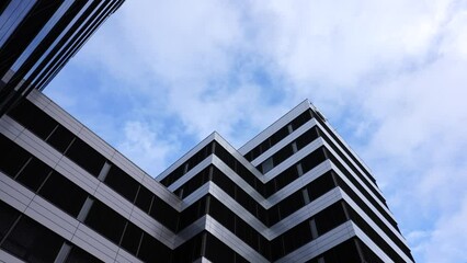 Modern multistory business center with dark windows and white cloud in sky