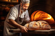 Baker removing fresh bread from a hot oven