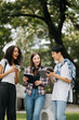 © Nuttapong punna - Young college students focusing on his school project, looking at laptop and tablet, discussing and working together at the campus park