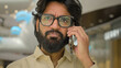 Portrait in office sad Arabian man in glasses talking phone answer business call Close up serious worried Indian male businessman executive CEO speaking distant communication talk mobile conversation