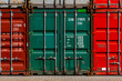 Stacked colorful containers in red, green, grey and bordeaux in the harbour of Duisburg Ruhrort inland port Germany. Logistics shipping background with metal square fronts of big boxs with doors.