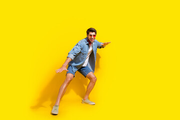 Poster - Full body photo of funky handsome man dressed denim shirt shorts surfing on imaginary board isolated on vivid yellow color background