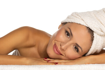 Wall Mural - Beauty portrait of a cheerful attractive half naked woman with a towel wrapped around her head with toothy smile lying on white background