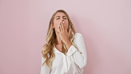 Poster - Sleepy young blonde woman yawning and stretching tired back, relaxing in pink morning glow, standing over isolated background, donning shirt