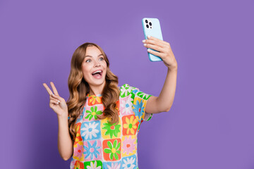 Photo of young excited girlfriend show v sign in shooting selfie hello symbol to all subscribers isolated on violet color background