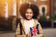 education, travel and people concept - smiling african american girl with british flag in city