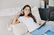 Cute pre-teen girl resting alone in bedroom with digital tablet device, wear wireless headphones enjoy favourite track, listen music on weekend at home. Young generation and tech usage, fun, leisure