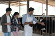 © amorn - agriculture industry, livestock, animal health and welfare. Dairy farmer male and female working in cowshed on dairy farm. Male and female veterinarian meeting and training in cowshed on dairy farm