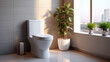 A beige bathroom with a white toilet and a green plant, with a window letting in natural light.