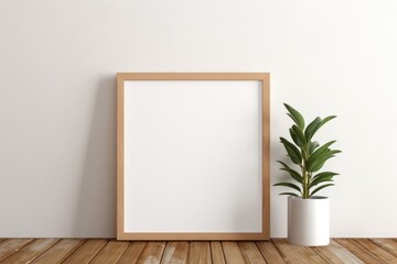 Empty wooden picture frame mockup on table leaning on the white wall with a green plant.