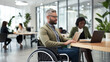 © MP Studio - Woman in a wheelchair and a man sitting at a desk in a well-lit, modern office environment, actively engaged in a collaborative discussion
