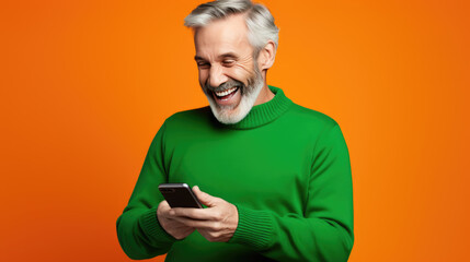 Senior man is using a smartphone against orange background.