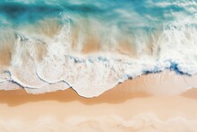 Aerial view of a shoreline with waves crashing onto the beach, the clear distinction between sea foam and golden sands illustrating the dynamic interface of land and sea.

