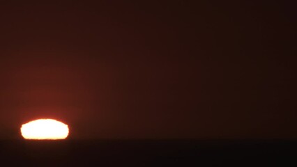 Wall Mural - Timelapse from complete blackness, the morning sun rises over body of water and becomes a bright and hot day.