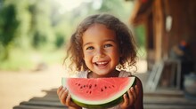 Happy little girl looks at the camera eating a watermelon in the garden, Smiling little girl eating a watermelon looking at the camera in the summer