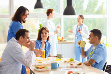 Canvas Print - Team of doctors having lunch at table in hospital kitchen