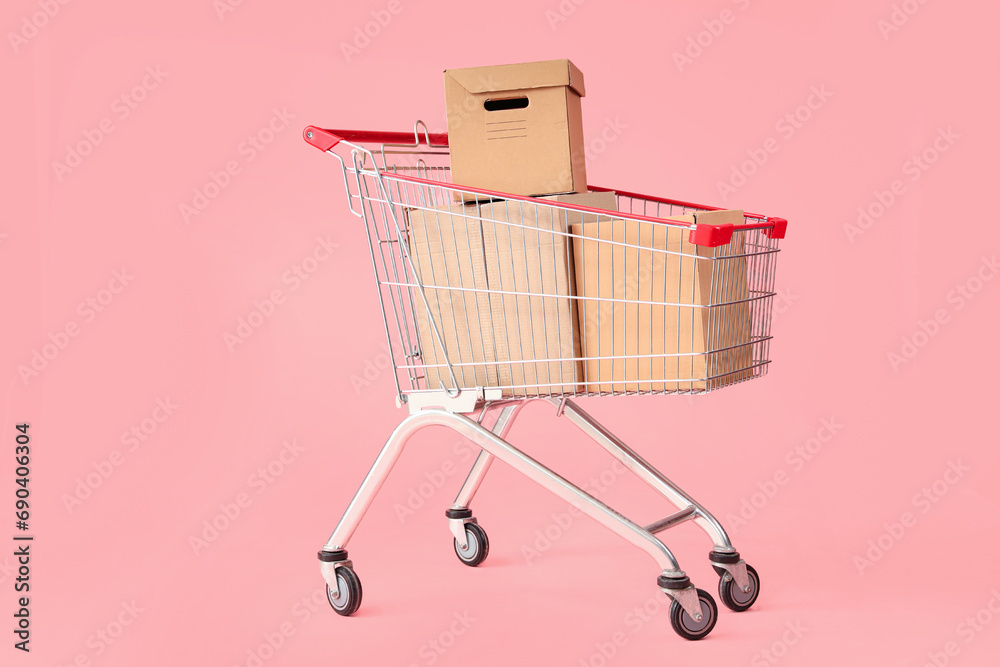 Shopping cart with cardboard boxes on pink background