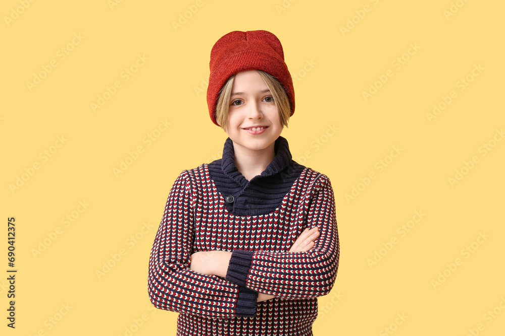 Cute little happy boy in winter clothes on yellow background