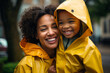 Portrait of cheerful mother and child wearing yellow raincoats under the rain. Enjoying all kinds of weather
