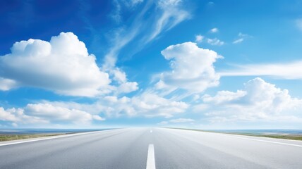 A straight open road leading towards the horizon under a bright blue sky with fluffy clouds