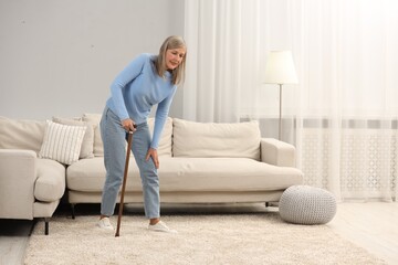 Poster - Mature woman with walking cane suffering from knee pain at home. Rheumatism symptom