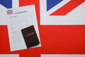 Wall Mural - Immigration to United Kingdom. Visa application form and passport on flag, top view. Space for text