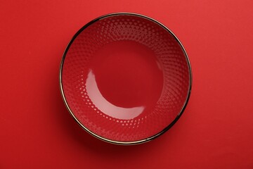 Beautiful ceramic bowl on red background, top view