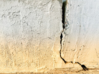 The base of the concrete wall settles, causing cracks in the brick wall