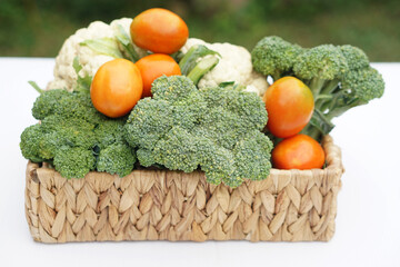 Wall Mural - Basket of organic vegetables from garden. Broccoli, cauliflower and tomatoes. Outdoor background. Concept, food ingredient. Healthy eating, source of vitamins, fiber and nutritions. Fresh from garden.