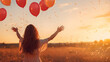Back silhouette view of an happy young woman releasing balloons in the sky at sunset in summer background with copy space