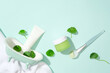 An unlabeled skincare set is displayed with fresh pennywort and props against a light blue background. Gotu kola helps reduce inflammation and redness caused by problems such as acne.