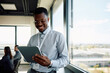 © Drazen - Happy black businessman working on digital tablet in office.