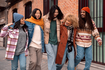 Wall Mural - multi-ethnic friends walking down the street together fondly laughing and talking happily