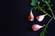 © E.O. - garlic cloves and leaves of arugula on a black stone board, top view, copy space