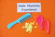 Comb, ballons and small pieces of paper. Equipment, prepared to do experiment about static electricity. Orange background.  Concept, Science lesson, fun and easy experiment. Education. Teaching aids. 