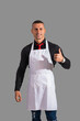 © theartofphoto - Attractive chef or waiter posing, wearing white apron and black shirt on gray background, in studio shot