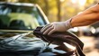 © NickArt - Close up photo of man's hands carefully polishing his car with a little black cloth on sunny spring day outdoors for professional car waxing and restorative grooming and detailing renewal