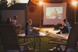 © Impact Photography - Friends spending summer evening outdoors watching a movie in a backyard open air cinema