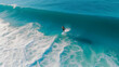 Aerial view of a surfer catching a wave in the blue ocean.