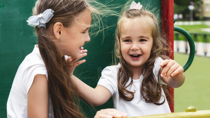 children play on the playground. Concept of summer, fun, family and relaxation. Two sisters having fun outside