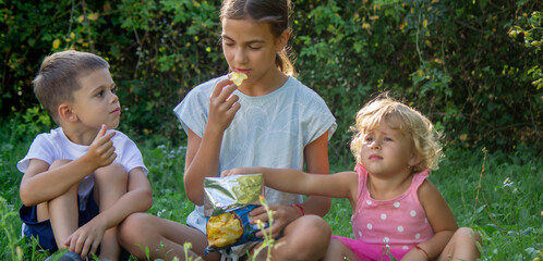 Wall Mural - happy children eating chips in the park. Selective focus.