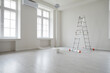 © Studio Romantic - Empty unfurnished room with ladder and paint bucket. Unfinished living room interior with white walls, floor and windows. Renovation. Repairs in apartment. Empty interior space