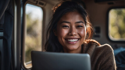 Smiling happy digital nomad young woman engaged in remote work inside her motorhome with her laptop , mobile lifestyle concept , free in van traveling, generating content, space for text
