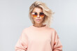 Fashionable confident blonde woman wearing trendy peach fuzz sweatshirt and sunglasses