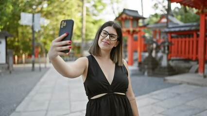 Poster - Vibrant selfie of a beautiful hispanic woman in glasses, all smiles capturing her fun-filled visit at the iconic fushimi inari-taisha temple, kyoto