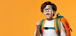 Young boy with curly dark hair and round glasses looks up in excitement, wearing a bright orange backpack, against a vibrant orange background. His expression is one of eager anticipation and joy