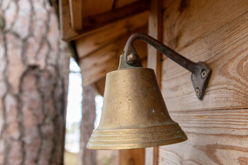 
A bronze bell hangs on a wooden wall