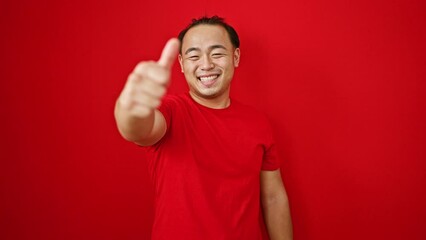 Sticker - Confident young chinese man standing over red background, flashing thumb up in an 'ok' sign, his smile radiating happiness and cool casual fashion.